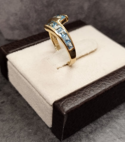 9ct Yellow Gold Crossover Ring Channel set with Light Blue Stones - Size M