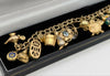 375 Hallmarked 9CT, YELLOW GOLD, 25X CHARMS ON CURBED BRACELET, 8", 35.1G, BOXED