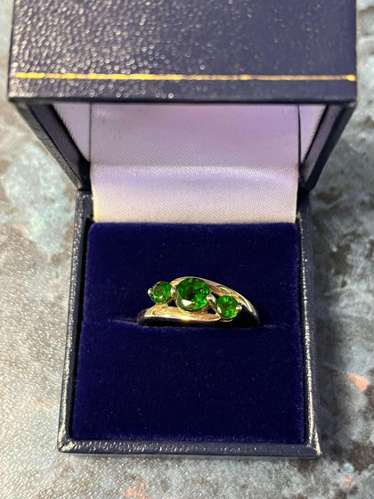 9CT GOLD RING WITH GREEN STONES.